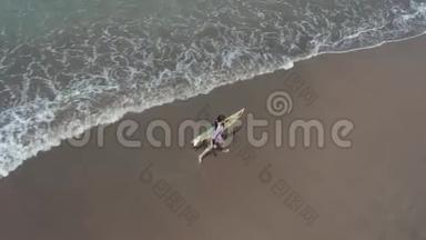 适合冲浪的女人从海边用冲浪板在海滩上奔跑。 现代生活方式。 夏季运动营和极限游泳